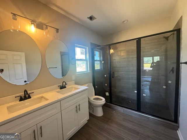 a bathroom with a double vanity sink toilet mirror and shower