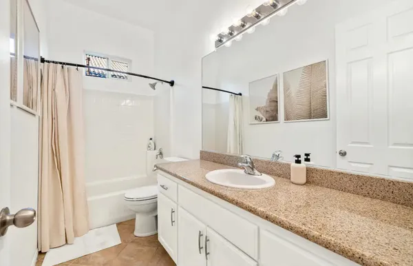 a bathroom with a granite countertop sink a toilet a mirror and shower