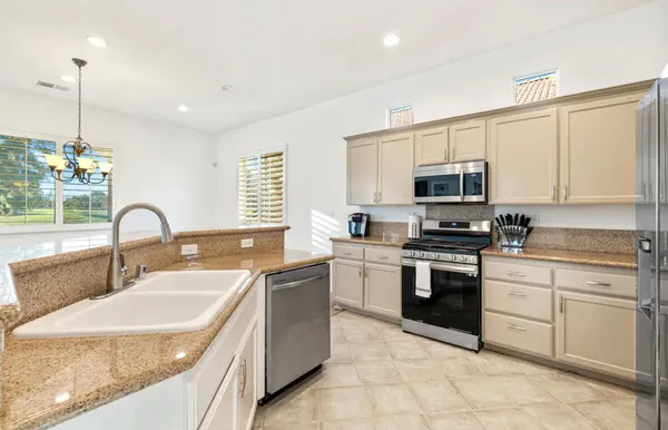 a kitchen with kitchen island granite countertop a sink white cabinets and stainless steel appliances