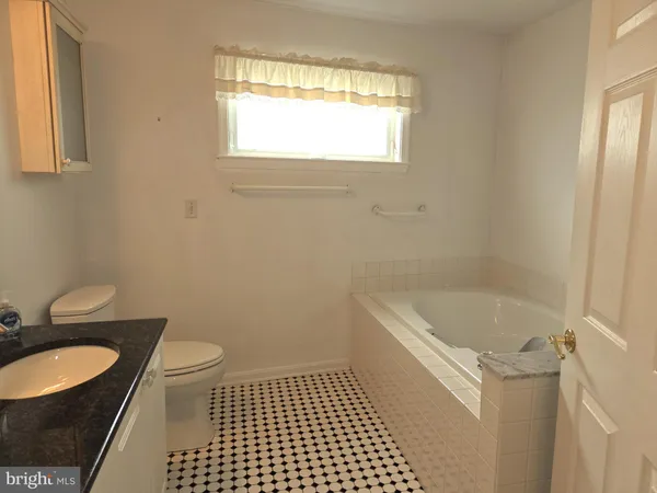 a bathroom with a granite countertop sink a toilet a window and shower