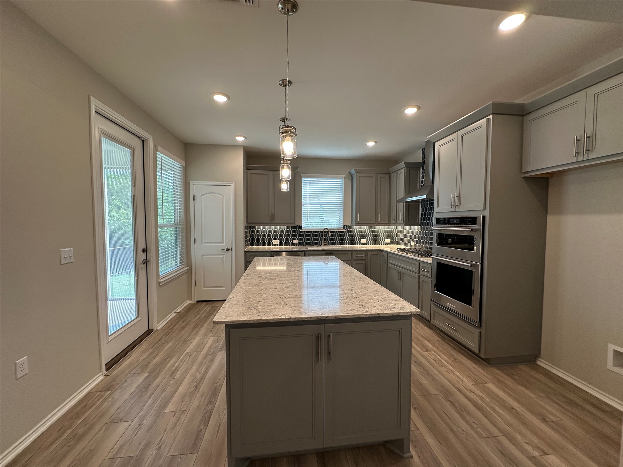 219 Coachsmith Street Georgetown, TX 78633 - Photo 8 of 25 Kitchen featuring gray cabinets, a center island, stainless steel appliances, decorative backsplash, and baseboards