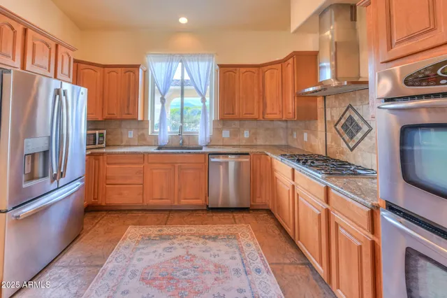 a kitchen with stainless steel appliances granite countertop a stove a sink dishwasher and a refrigerator