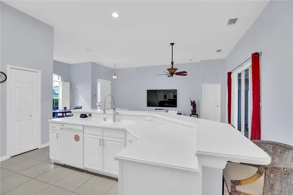 a large white kitchen with a stove a sink dishwasher a dining table and chairs with wooden floor