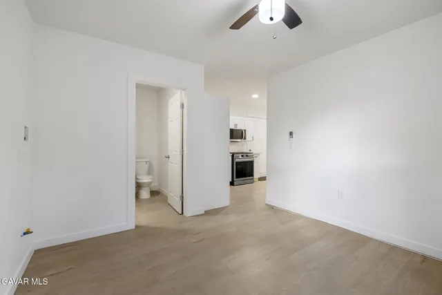 an empty room with chandelier fan and refrigerator