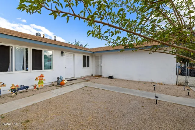 a backyard of a house with potted plants and large tree