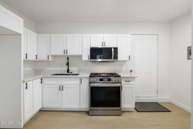 a kitchen with stainless steel appliances granite countertop a stove a sink and a microwave