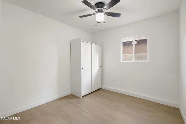 an empty room with a window and a fan