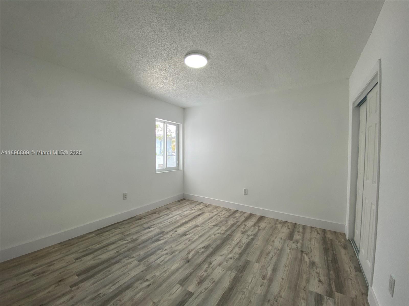 46 Northwest 44th Street, Unit 46 Miami, FL 33127 - Photo 11 of 16 wooden floor in an empty room with a window