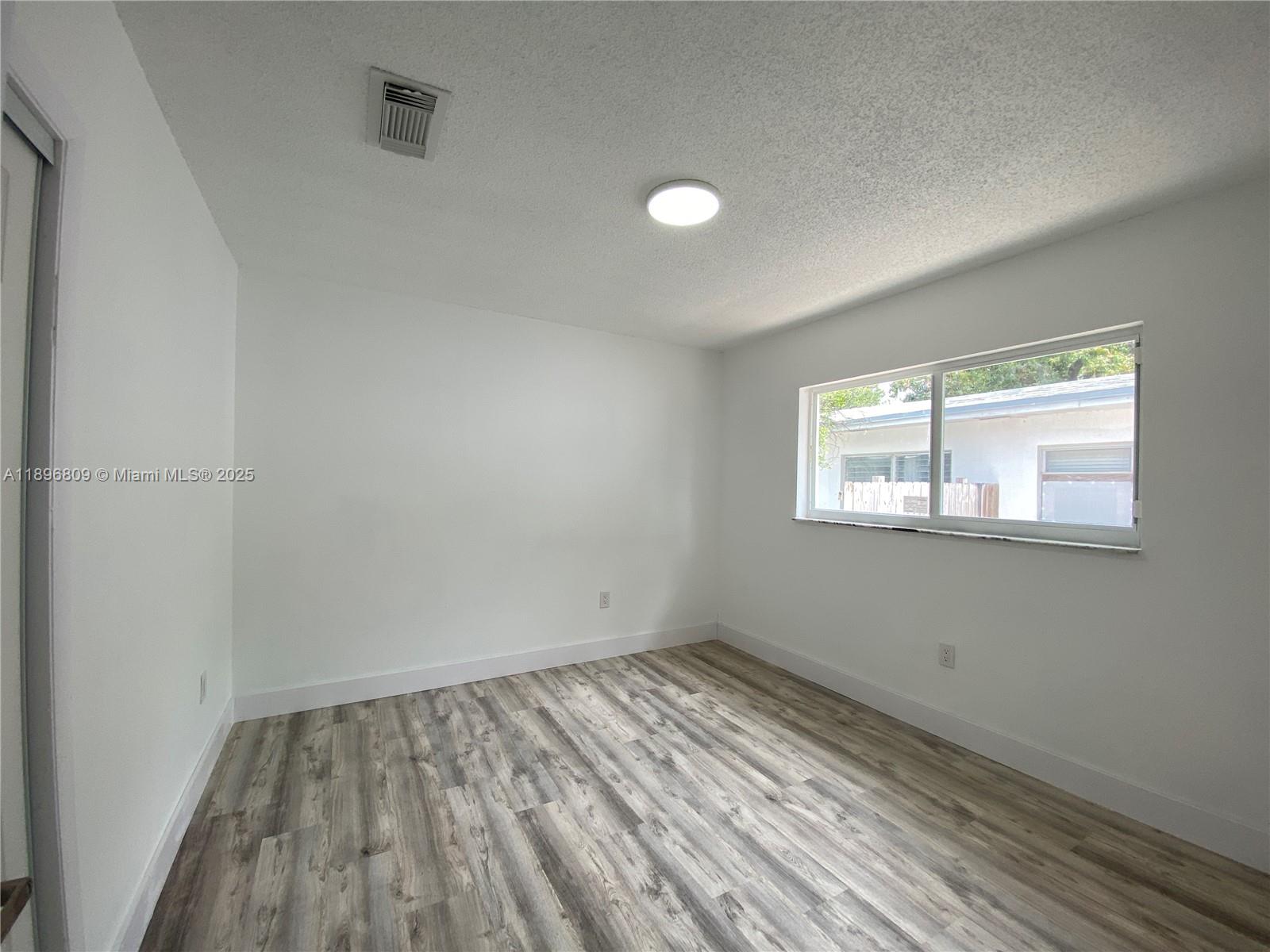 46 Northwest 44th Street, Unit 46 Miami, FL 33127 - Photo 12 of 16 a view of empty room with wooden floor and fan