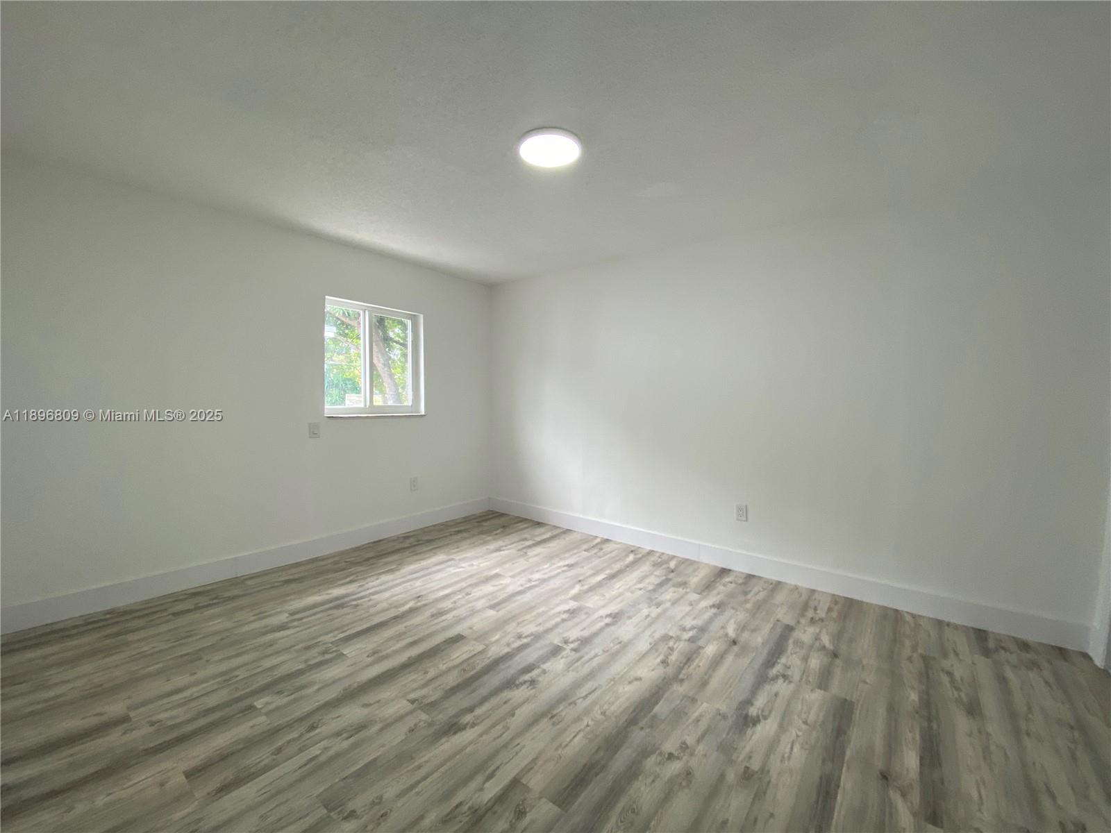 46 Northwest 44th Street, Unit 46 Miami, FL 33127 - Photo 8 of 16 an empty room with wooden floor and windows