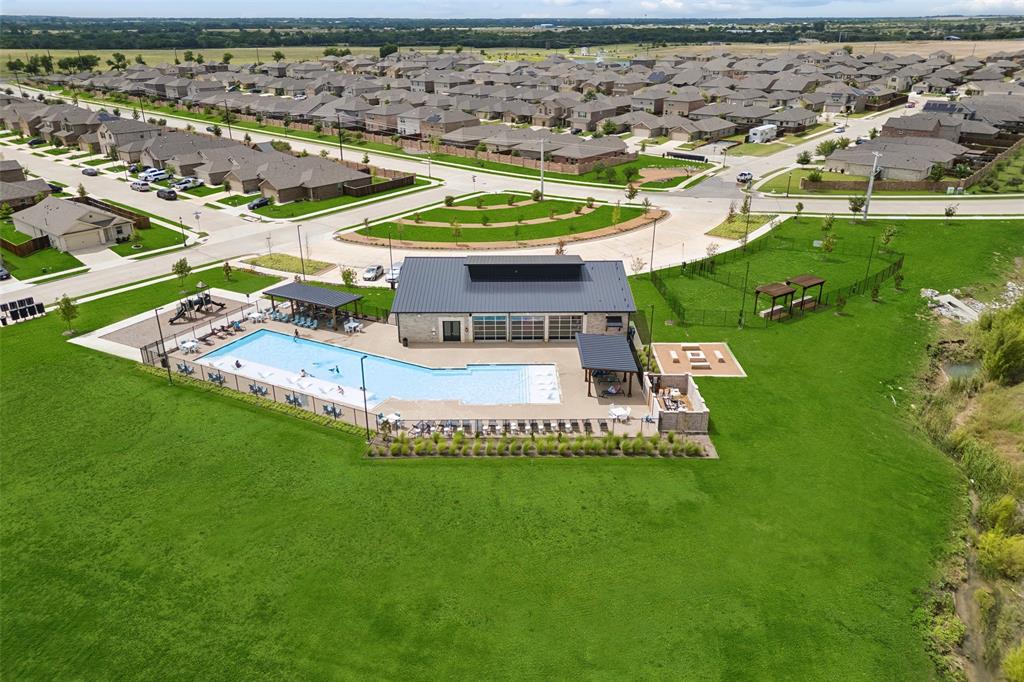 14163 Kempt Drive Pilot Point, TX 76258 - Photo 25 of 29 This aerial view highlights the exceptional amenities available to Mobberly Farms residents, including a resort-style pool, contemporary clubhouse, outdoor gathering spaces, playground, and beautifully maintained greenbelts that enhance the community's welcoming atmosphere and active lifestyle.