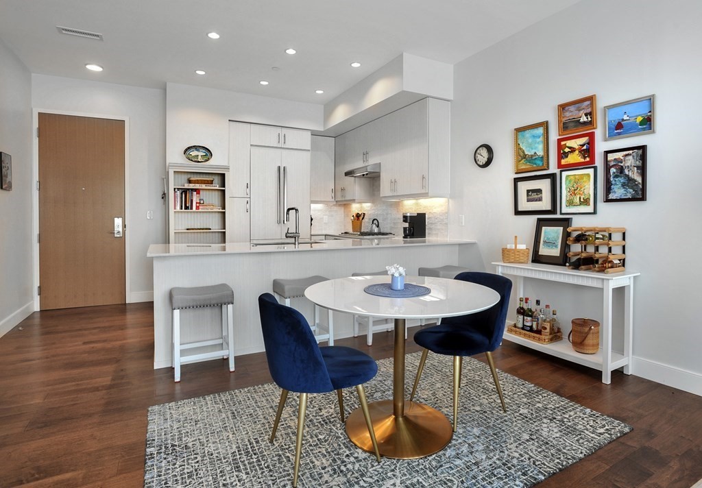 10 Shipyard Drive, Unit 401 Hingham, MA 02043 - Photo 8 of 24 a kitchen with stainless steel appliances kitchen island granite countertop a sink a stove a dining table and chairs