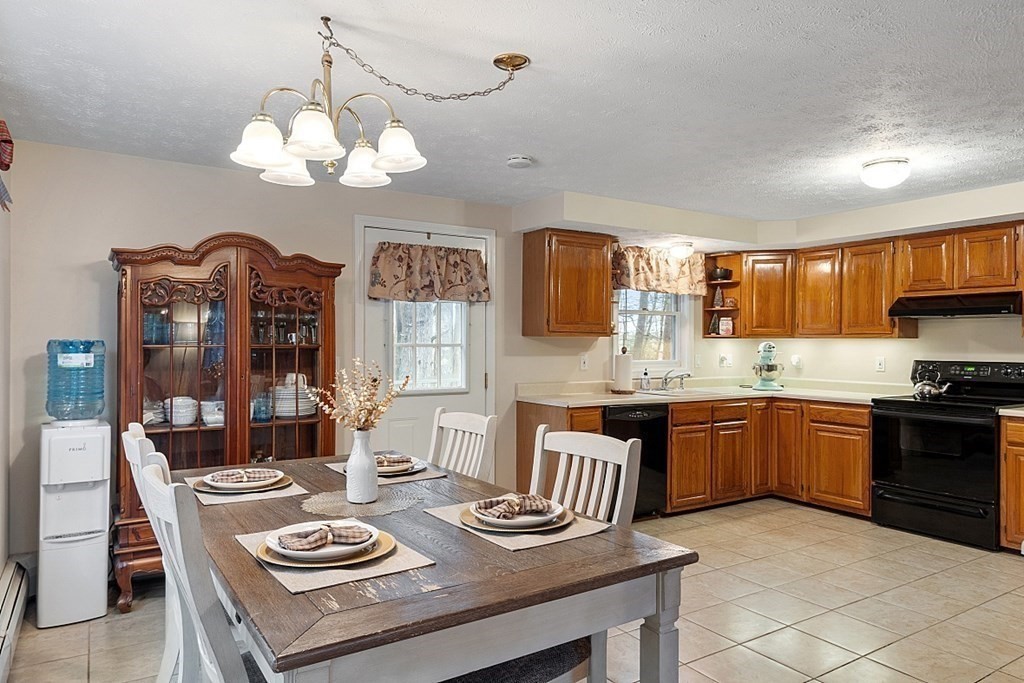 628 Teel Road Winchendon, MA 01475 - Photo 8 of 38 a kitchen with a kitchen island hardwood floor sink stove dining table and chairs