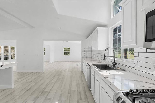 a kitchen with stainless steel appliances white cabinets and a stove top oven