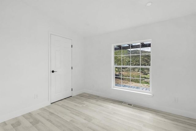 an empty room with wooden floor fan and windows