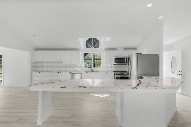a large kitchen with a wooden floor and white cabinets