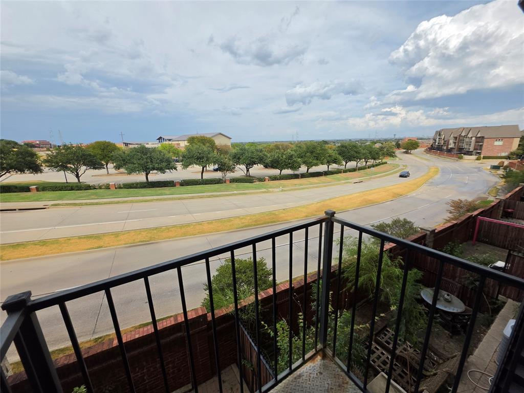 809 Rockingham Drive Irving, TX 75063 - Photo 25 of 30 Balcony with black metal railing overlooking a paved roadway with a landscaped median