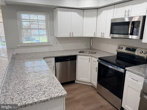 a kitchen with stainless steel appliances kitchen island granite countertop a stove a sink and a microwave