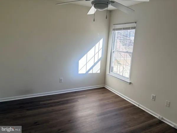 an empty room with wooden floor chandelier fan and windows