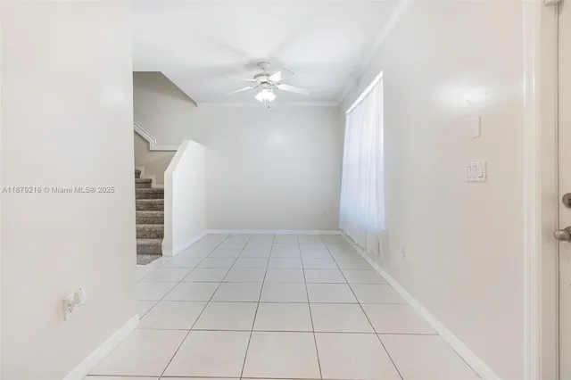 a view of an empty room with stairs and chandelier fan