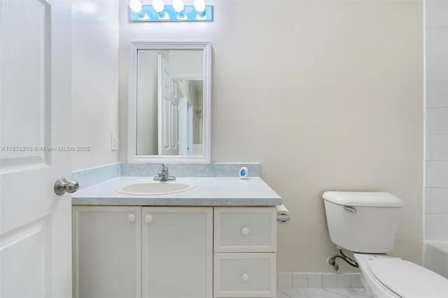 a bathroom with a granite countertop toilet sink and mirror