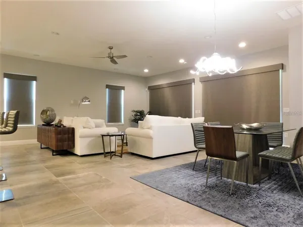 a living room with furniture kitchen view and a chandelier