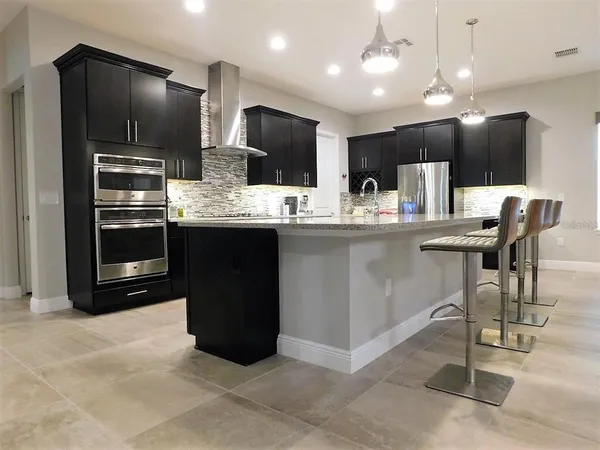 a kitchen with kitchen island stainless steel appliances a sink cabinets and wooden floor