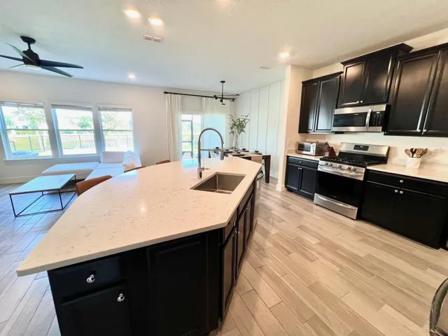 a large kitchen with kitchen island granite countertop lots of counter top space a sink and stainless steel appliances