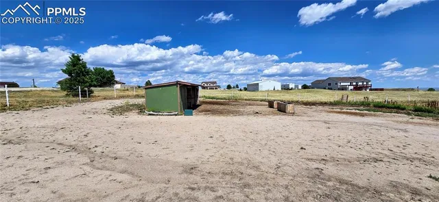 a view of a dry yard with wooden fence