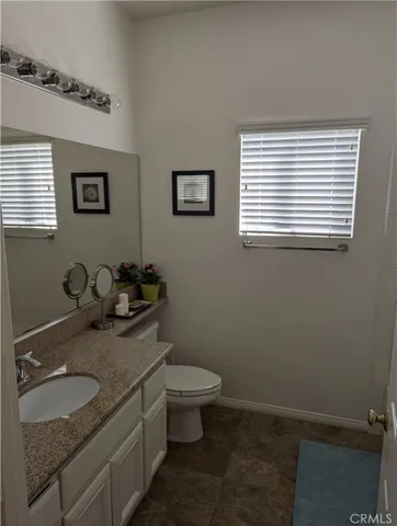 a bathroom with a granite countertop sink and a toilet