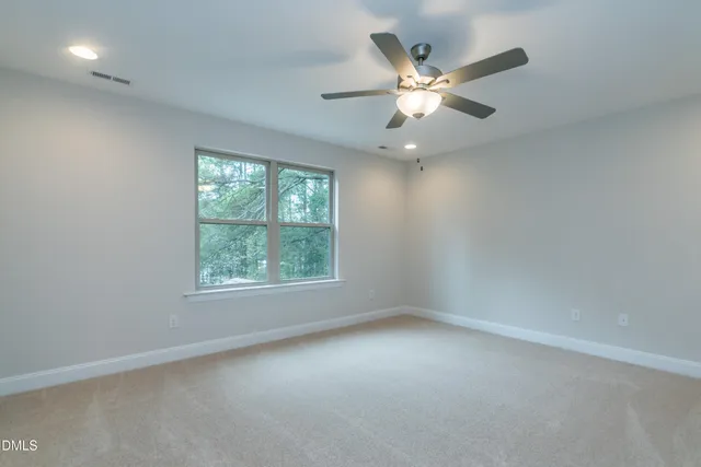 an empty room with chandelier fan and windows