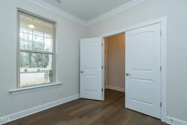 an empty room with wooden floor chandelier fireplace and windows