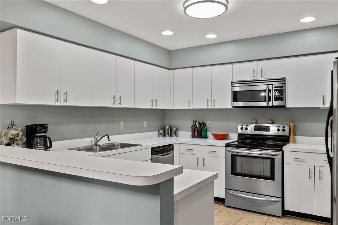 6891 Pentland Way, Unit 91 Fort Myers, FL 33966 - Photo 11 of 33 a kitchen with stainless steel appliances granite countertop a sink a stove and microwave with wooden cabinets
