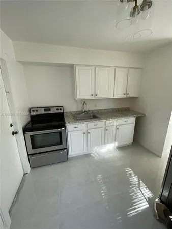 a kitchen with stainless steel appliances a stove a sink and white cabinets