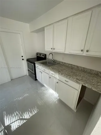 a kitchen with granite countertop white cabinets and sink