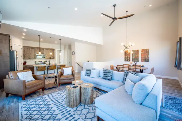 a living room with furniture kitchen view and a chandelier