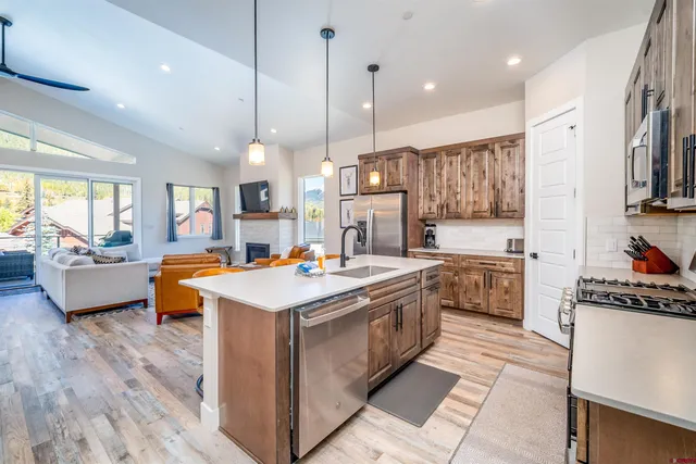 a kitchen with stainless steel appliances granite countertop a stove top oven a refrigerator a sink and a view of living room