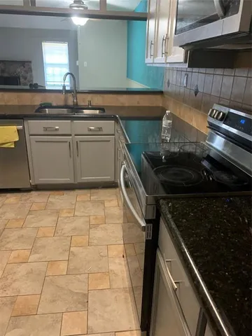 a kitchen with a sink a stove cabinets and a window