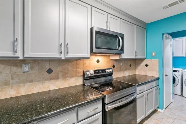 a kitchen with stainless steel appliances granite countertop white cabinets and stove
