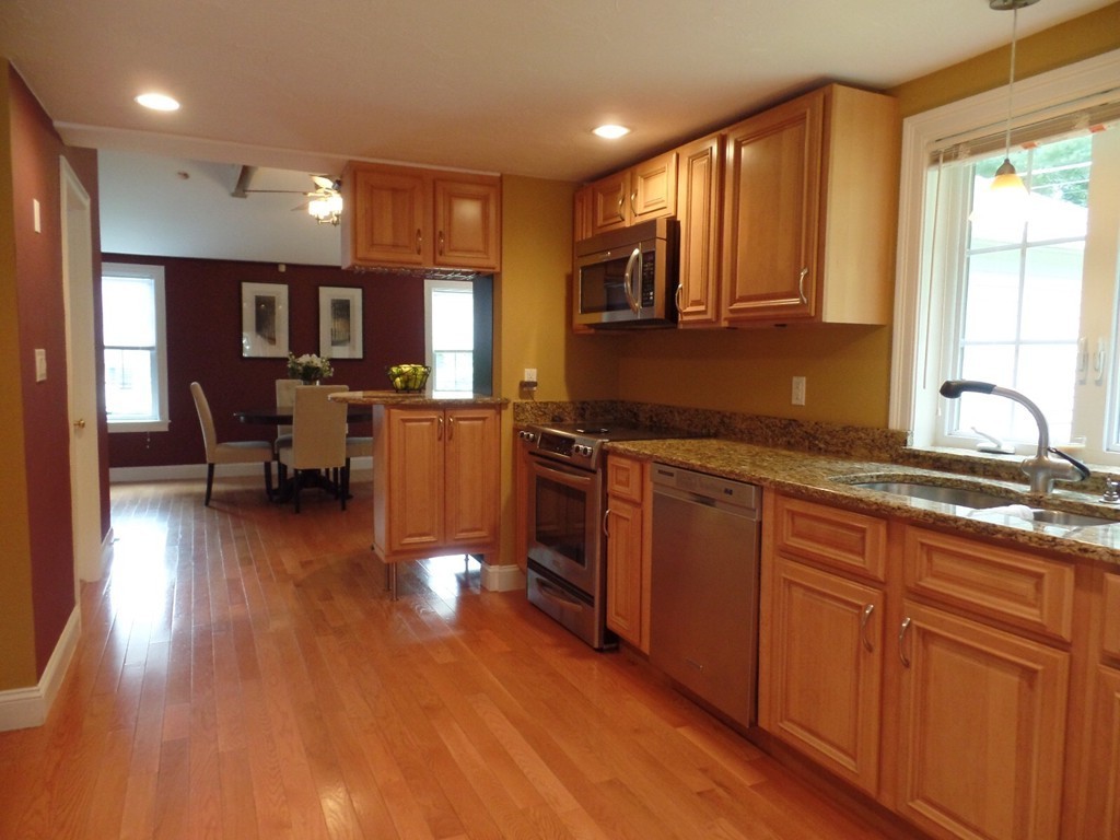 234 Stonebridge Road Wayland, MA 01778 - Photo 5 of 20 a kitchen with stainless steel appliances granite countertop wooden cabinets a sink a stove a dining table and chairs