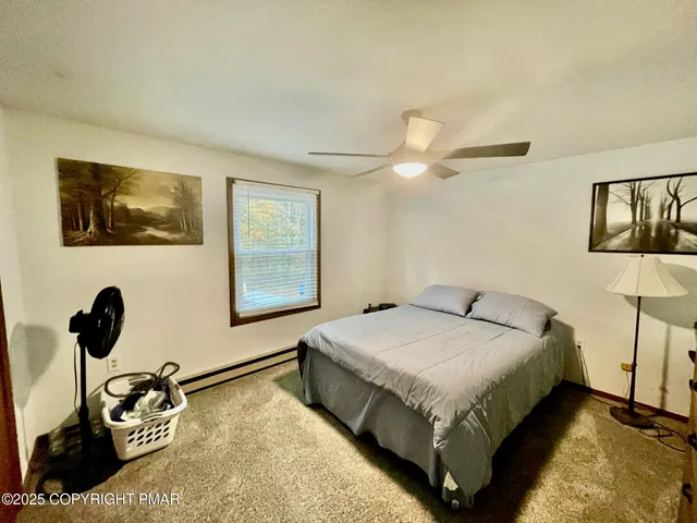 a bedroom with a bed lamp and paintings on the wall