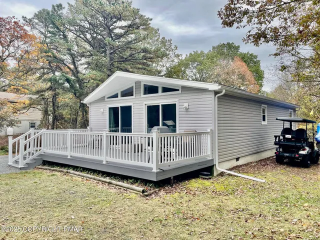 a view of a house with a wooden deck and a yard