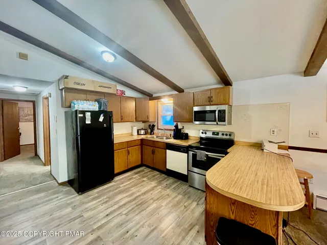 a kitchen with stainless steel appliances kitchen island granite countertop a refrigerator a stove top oven a sink dishwasher and a dining table with wooden floor