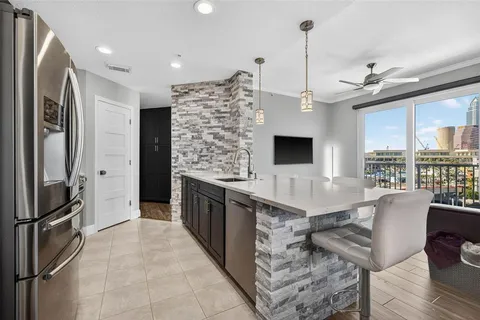 a large kitchen with kitchen island granite countertop a refrigerator oven a sink dishwasher a dining table and chairs with wooden floor