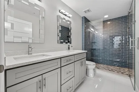 a bathroom with a double vanity sink toilet and shower