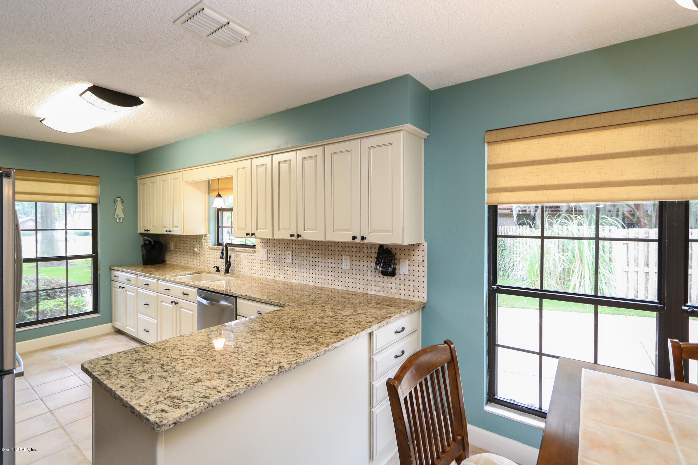 3141 Nautilus Road Middleburg, FL 32068 - Photo 12 of 43 a kitchen with granite countertop wooden cabinets a stove a sink and a large window