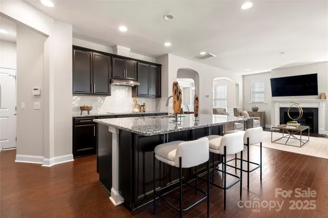 a kitchen with stainless steel appliances granite countertop a stove top oven a sink dishwasher a dining table and chairs