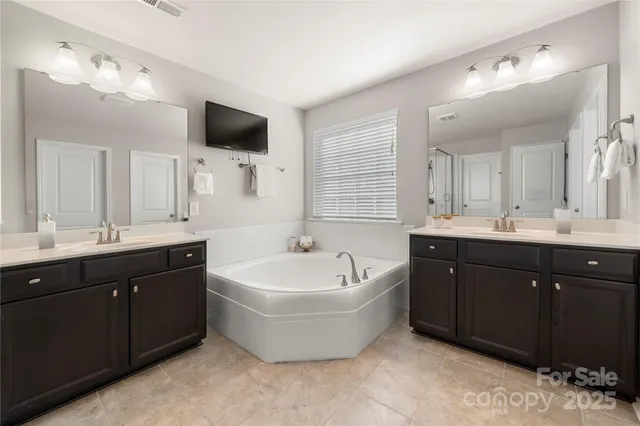 a spacious bathroom with a tub double sink and mirror
