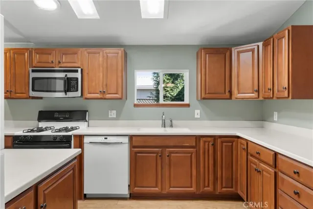 a kitchen with stainless steel appliances granite countertop a sink a stove a microwave and wooden cabinets