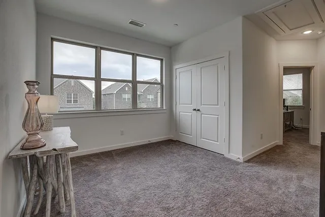 a spacious bedroom with a bed and a flat tv screen on dresser